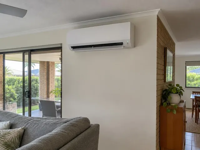 Wall-mounted split system with open louvre in a modern living room with sliding glass doors in Hope Island