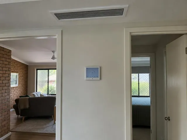 Ceiling ducted air conditioning grille and wall controller in a painted hallway in Pimpama
